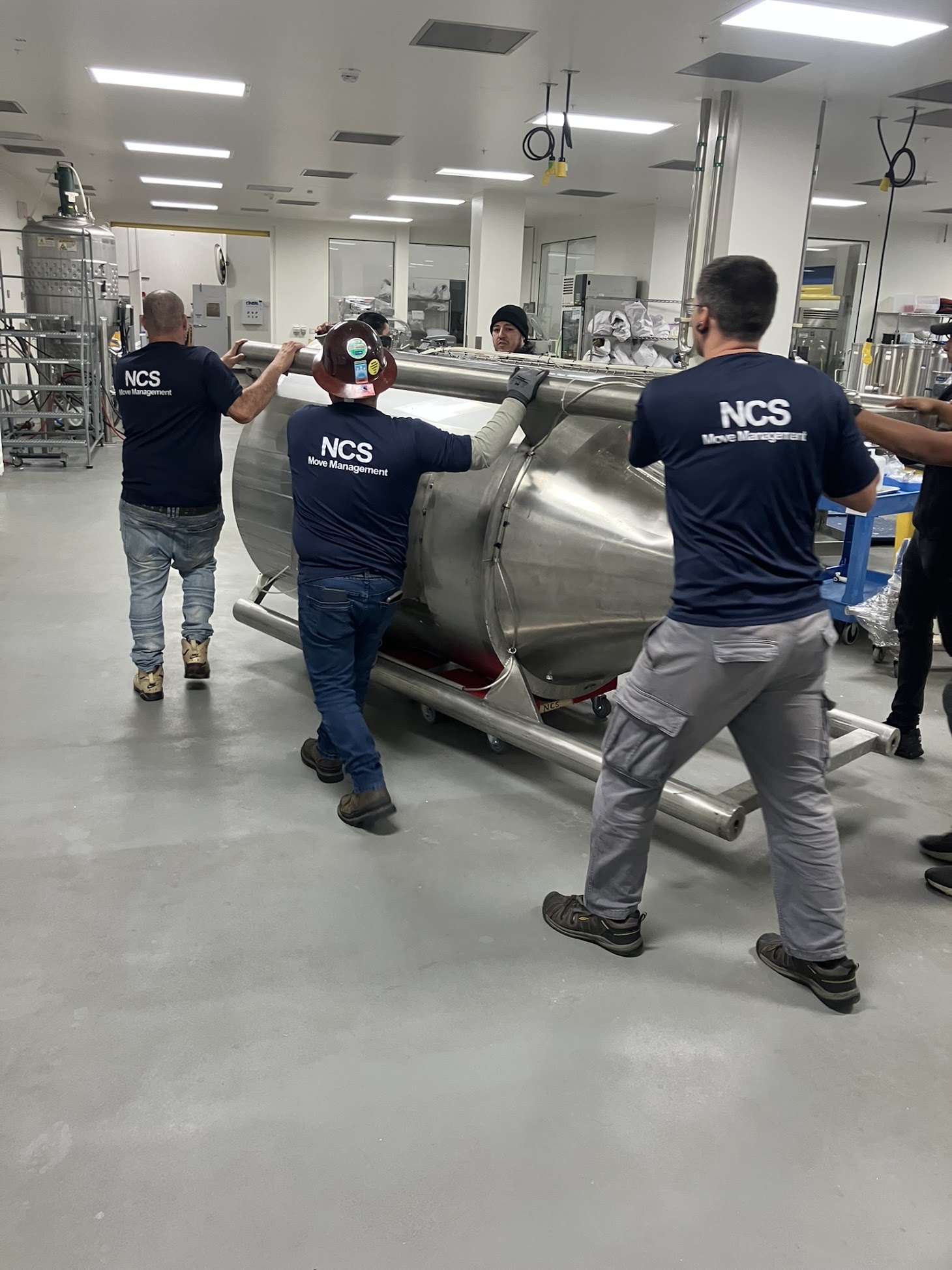 NCS crew relocating a stainless bioreactor in a cleanroom lab
