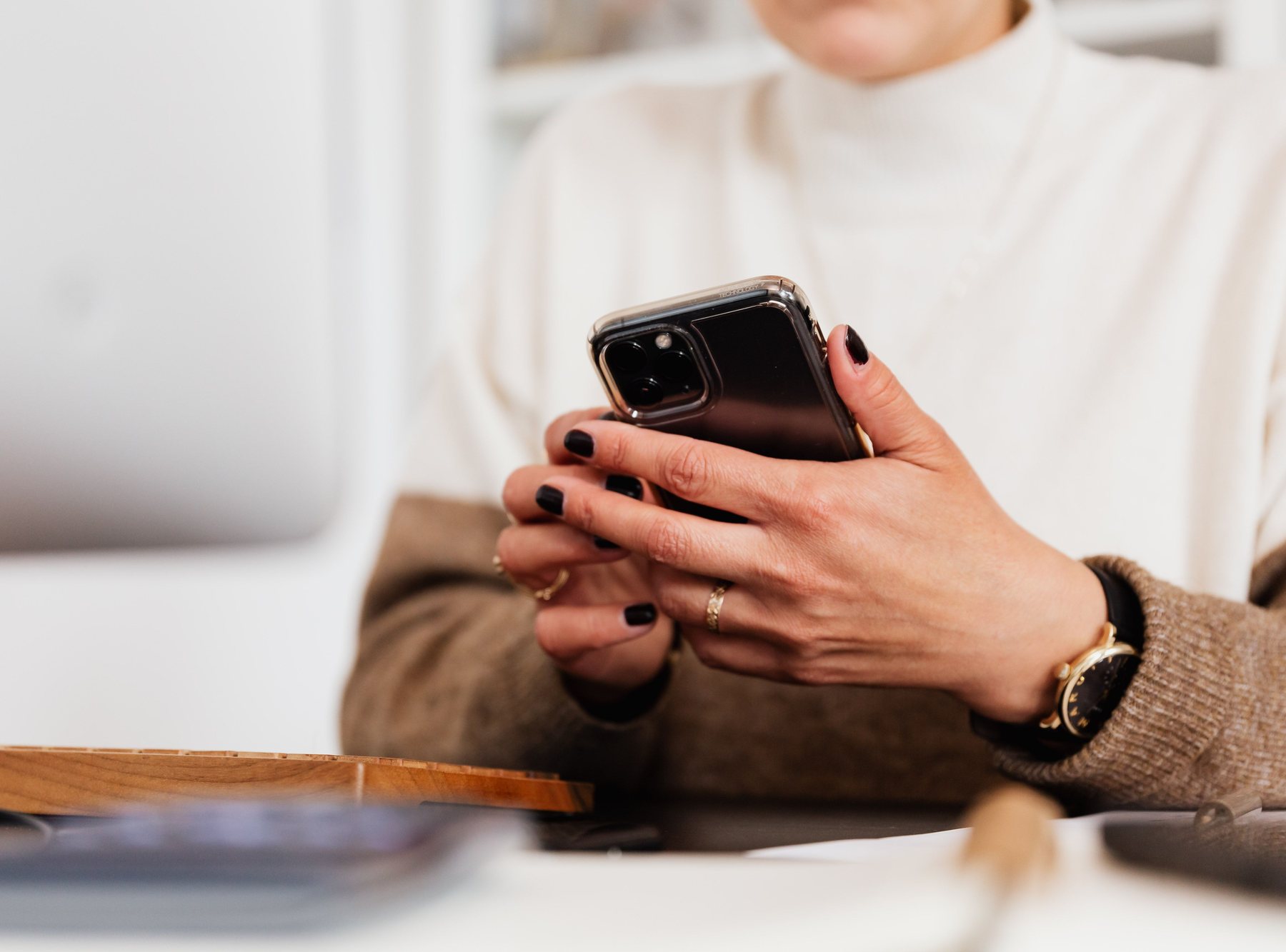 Person holding a mobile phone at a desk