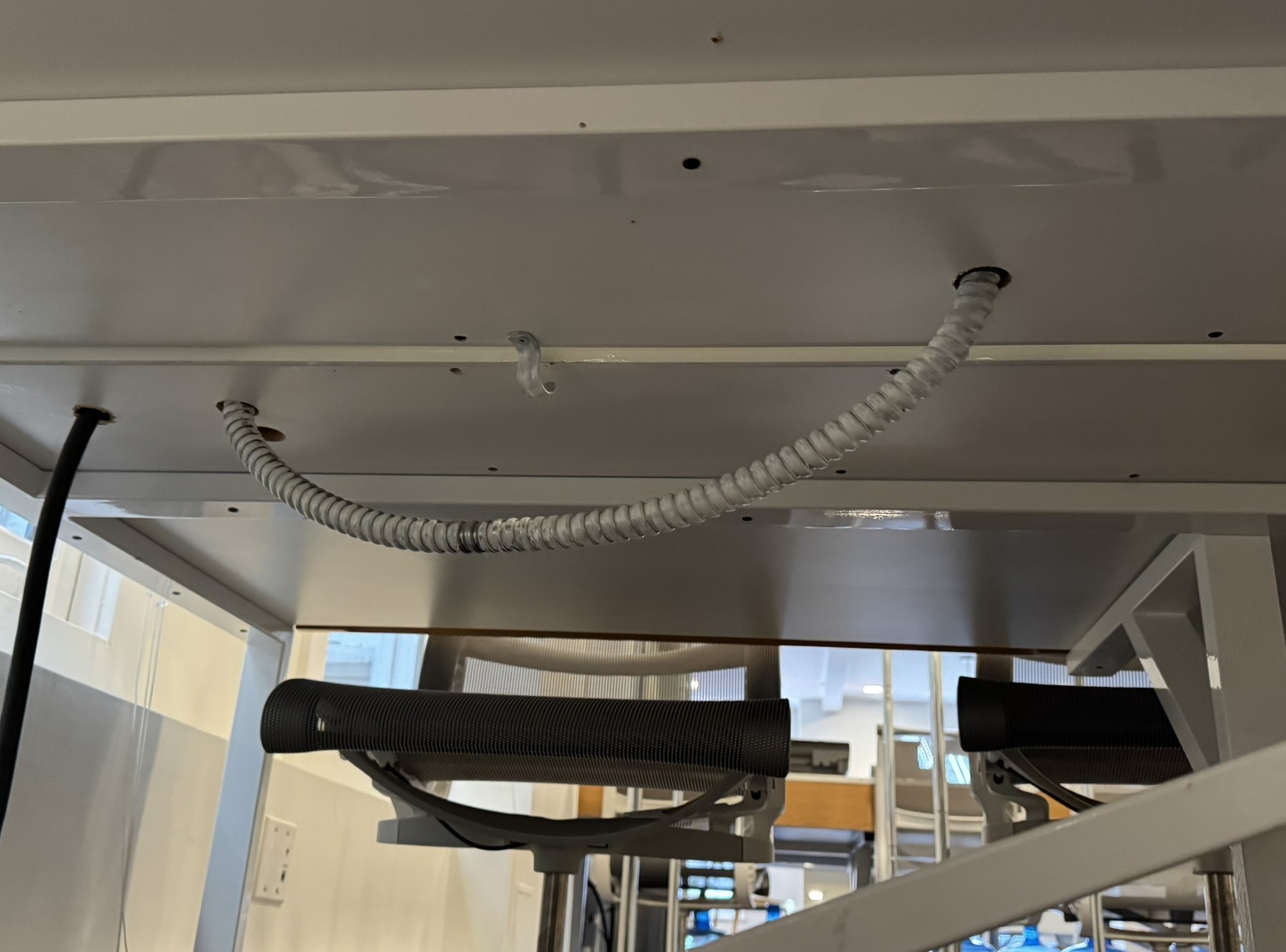 Flexible conduit and cable routed beneath a desk after an NCS office relocation